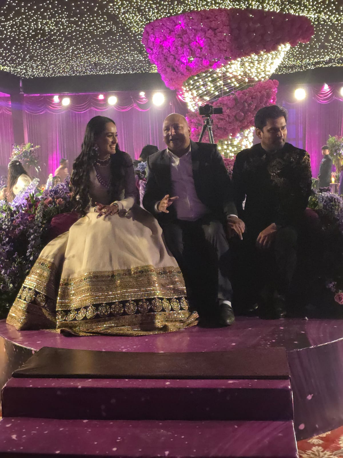 Manoj Garg seated with a couple beneath a canopy of lights
